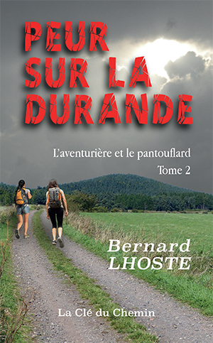 Couverture du livre « Peur sur la Durande » de Bernard Lhoste. Deux randonneuses marchent sur un chemin de campagne vers des collines boisées sous un ciel nuageux traversé par le soleil. Titre rouge dramatique, sous-titre « L’aventurière et le pantouflard – Tome 2 », mention de l’éditeur La Clé du Chemin.