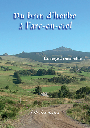 Couverture de livre montrant un paysage rural verdoyant avec collines, champs et chemin de terre sous un ciel bleu. Titre « Du brin d’herbe à l’arc-en-ciel » et sous-titre « Un regard émerveillé… », signé Lili des orties, évoquant nature, sérénité et contemplation.