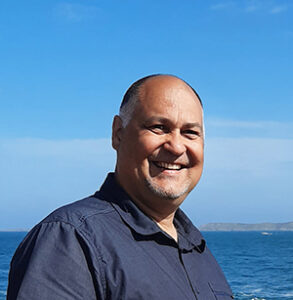 Photo de Thierry Dadolle portant une chemise bleue avec en arrière-plan un fond de mer bleue.